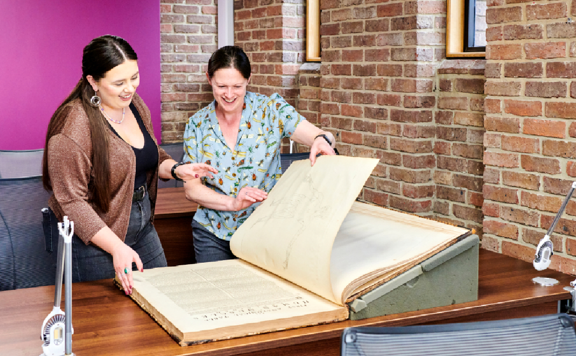 A student and staff member studying a written source in the special collections